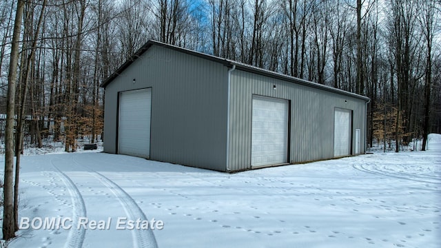 snow covered garage featuring a detached garage
