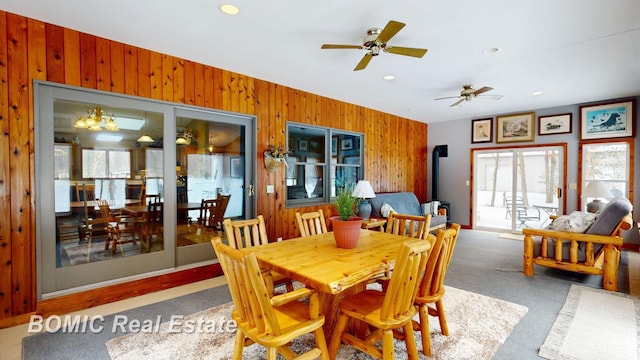 dining space with wood walls, a ceiling fan, carpet flooring, and recessed lighting