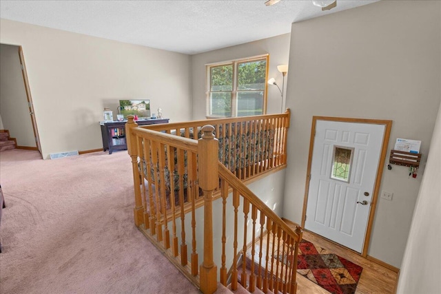 staircase featuring a textured ceiling and carpet flooring