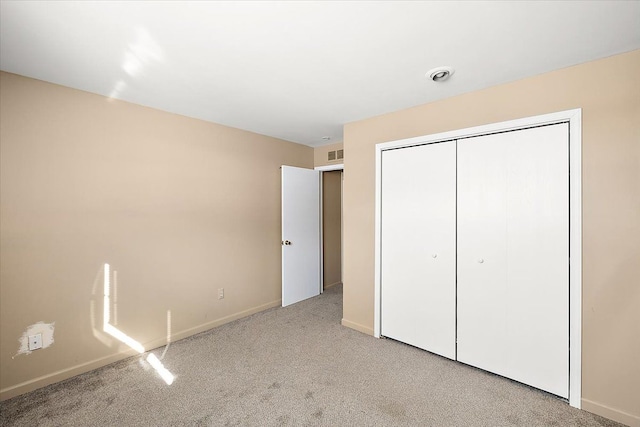 unfurnished bedroom with baseboards, visible vents, a closet, and light colored carpet