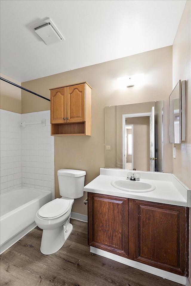 full bathroom featuring visible vents, toilet, wood finished floors, vanity, and washtub / shower combination