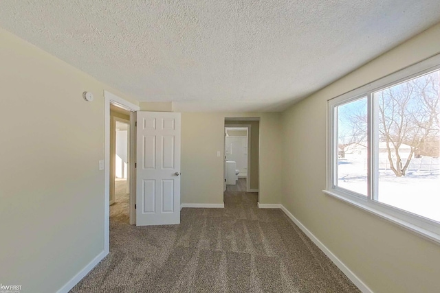 unfurnished bedroom featuring a textured ceiling and dark carpet