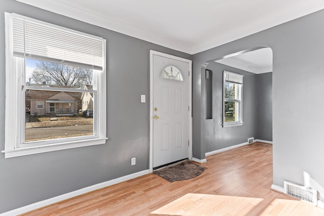 entryway featuring arched walkways, visible vents, baseboards, and wood finished floors