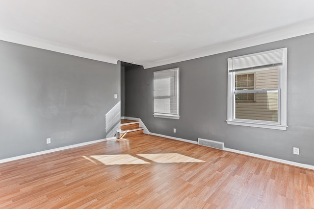 spare room with wood finished floors, visible vents, and baseboards