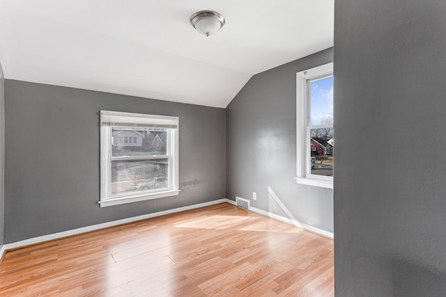 bonus room featuring lofted ceiling, visible vents, baseboards, and wood finished floors