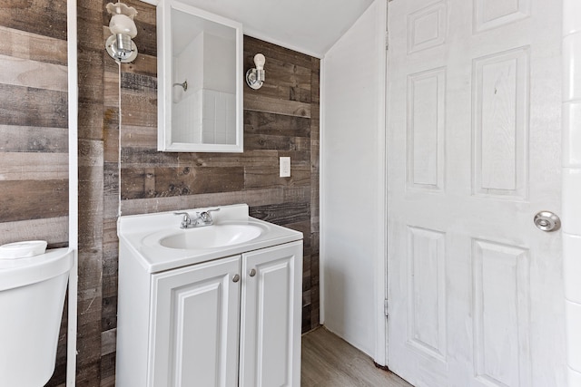 bathroom with wood finished floors, vanity, toilet, and wooden walls