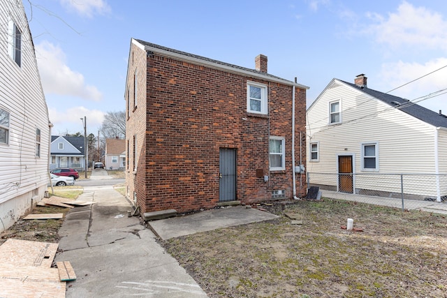 rear view of house with a chimney, fence, and brick siding