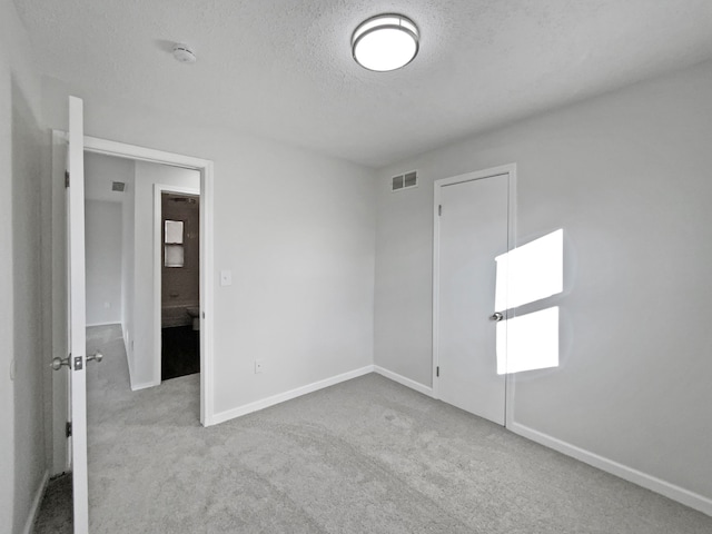 carpeted empty room with a textured ceiling