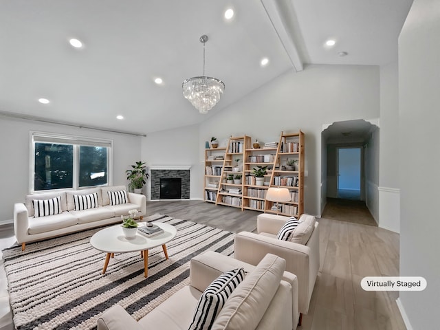 living room featuring a fireplace, vaulted ceiling with beams, light wood-type flooring, and a notable chandelier