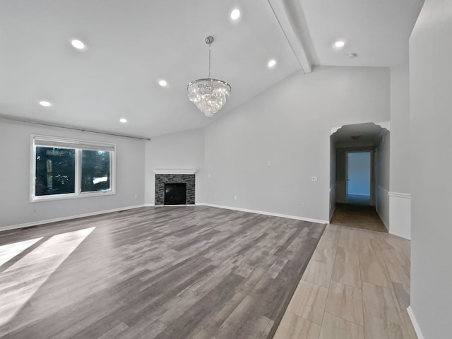 unfurnished living room featuring a stone fireplace, vaulted ceiling with beams, an inviting chandelier, and light wood-type flooring