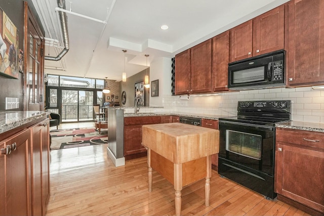 kitchen featuring decorative backsplash, pendant lighting, light stone countertops, and black appliances