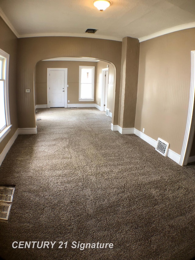 empty room with ornamental molding and carpet flooring