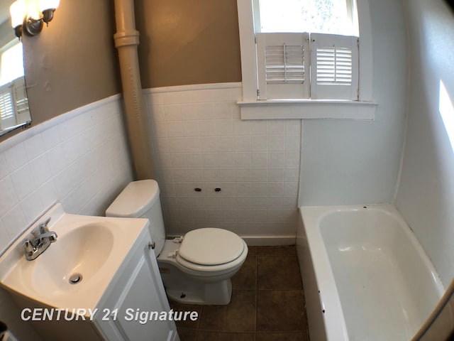 bathroom featuring tile patterned flooring, toilet, a tub, tile walls, and vanity