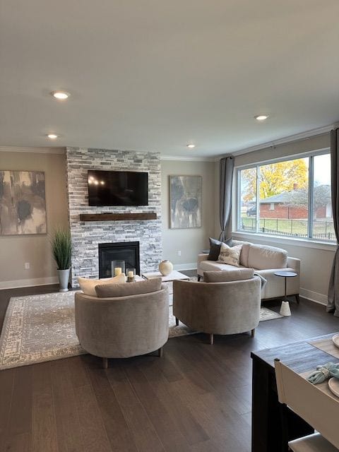 living room featuring a stone fireplace, crown molding, and dark hardwood / wood-style floors