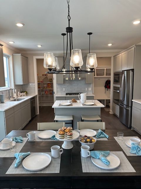 kitchen featuring a center island with sink, gray cabinetry, hanging light fixtures, sink, and appliances with stainless steel finishes