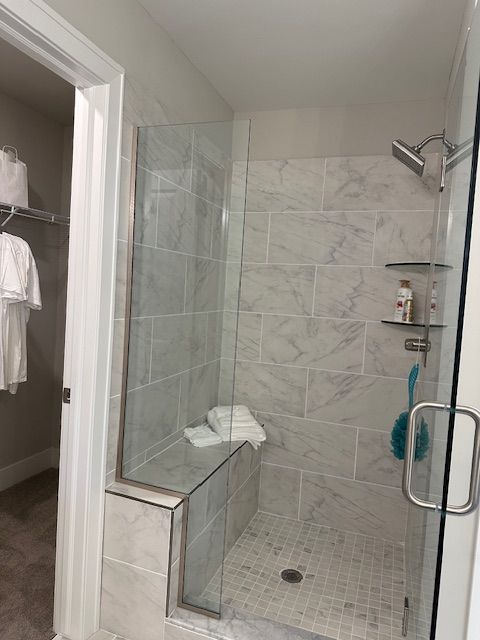bathroom featuring a stall shower, a spacious closet, and baseboards