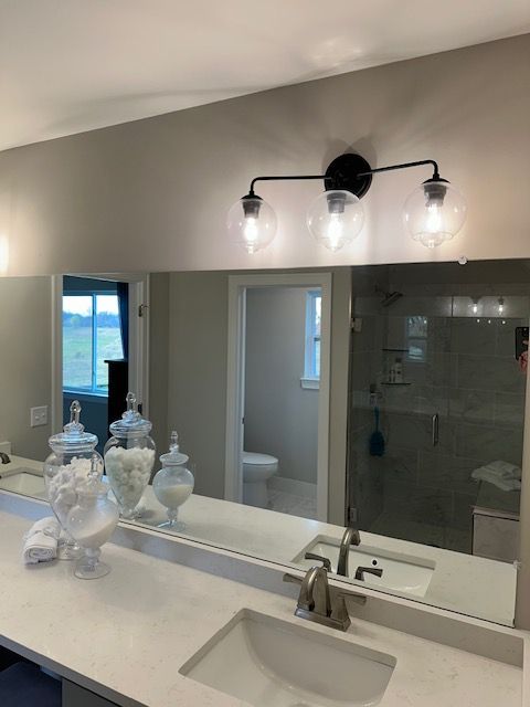 bathroom with a stall shower, a sink, toilet, and double vanity
