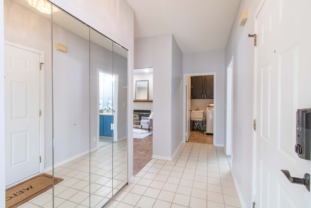 corridor with light tile patterned floors, baseboards, and washer / dryer