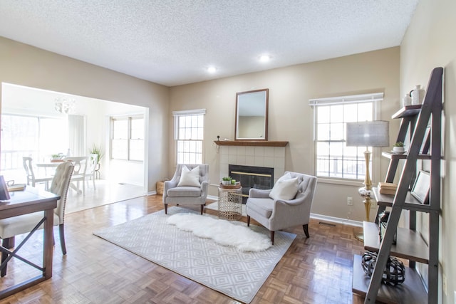 living area featuring a healthy amount of sunlight, baseboards, and a tile fireplace