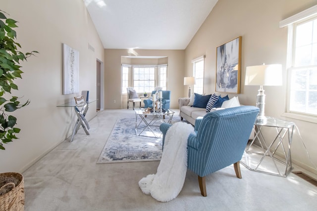 living room featuring light carpet, high vaulted ceiling, a wealth of natural light, and baseboards