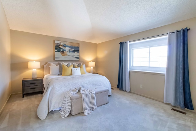 bedroom with baseboards, visible vents, a textured ceiling, and light colored carpet