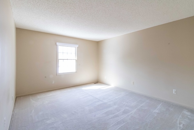 unfurnished room featuring light colored carpet and a textured ceiling