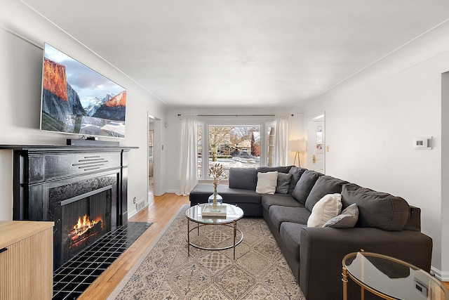 living room with hardwood / wood-style flooring and a tiled fireplace