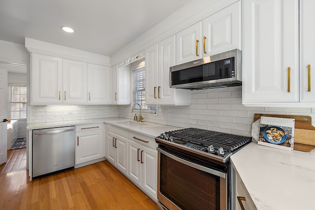 kitchen featuring sink, light wood-type flooring, white cabinetry, plenty of natural light, and stainless steel appliances