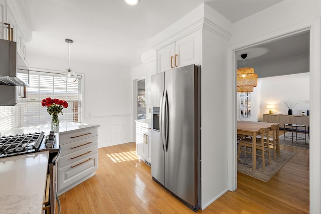 kitchen featuring decorative light fixtures, light hardwood / wood-style floors, stainless steel appliances, and white cabinets