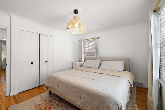 bedroom featuring hardwood / wood-style flooring, crown molding, and a closet