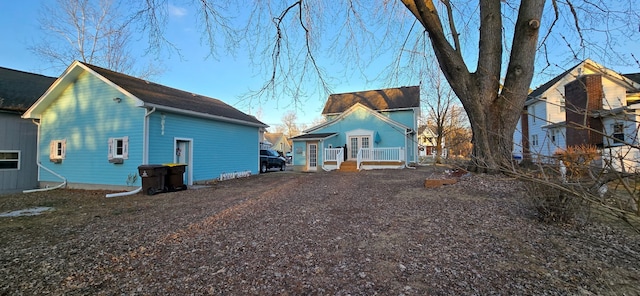 back of property with a porch and gravel driveway