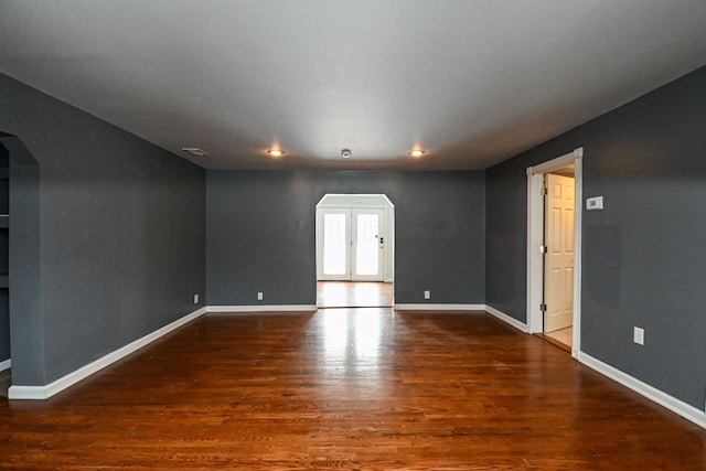 unfurnished room featuring baseboards, visible vents, arched walkways, dark wood finished floors, and french doors