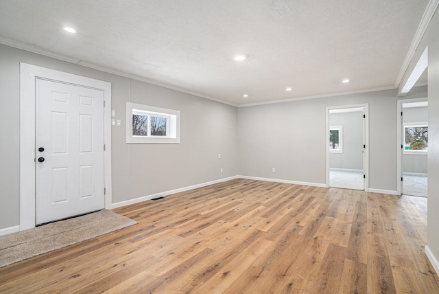 interior space with baseboards, crown molding, a textured ceiling, and light wood finished floors