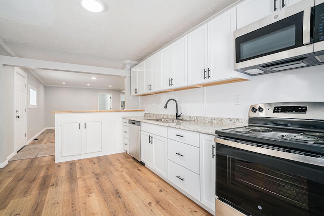 kitchen featuring a peninsula, appliances with stainless steel finishes, a sink, and white cabinets