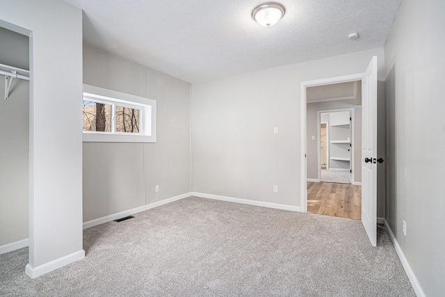 unfurnished bedroom featuring baseboards, carpet flooring, visible vents, and a textured ceiling