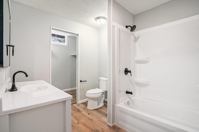 bathroom with toilet, tub / shower combination, vanity, a textured ceiling, and wood finished floors