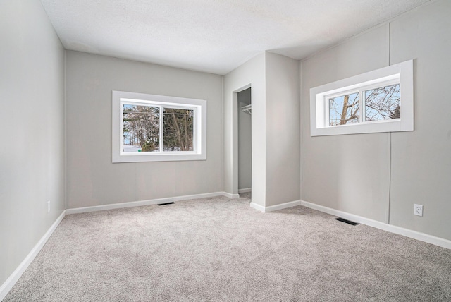 unfurnished bedroom with carpet, a closet, visible vents, a textured ceiling, and baseboards