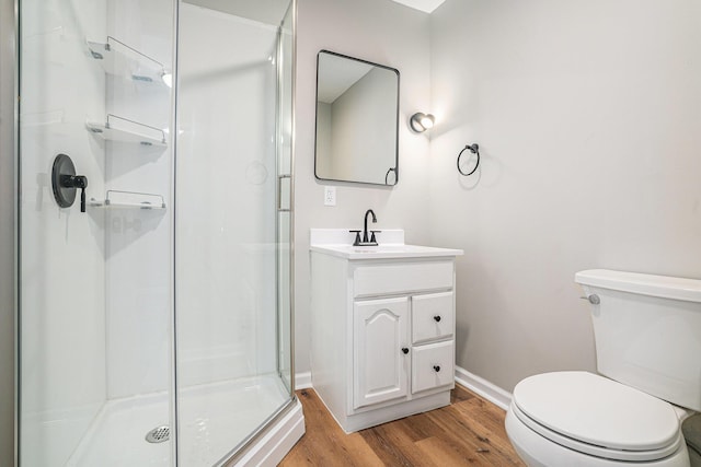 full bath with toilet, vanity, a shower stall, wood finished floors, and baseboards