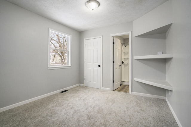 unfurnished bedroom with light carpet, a textured ceiling, visible vents, and baseboards