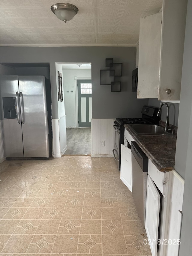 kitchen featuring sink, ornamental molding, black appliances, and white cabinets