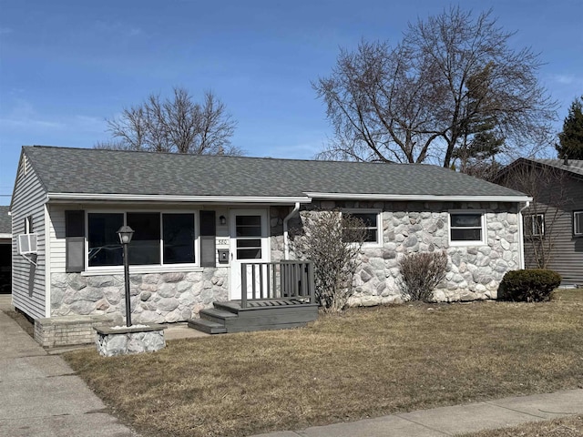 view of front of home with a front yard, stone siding, and a shingled roof