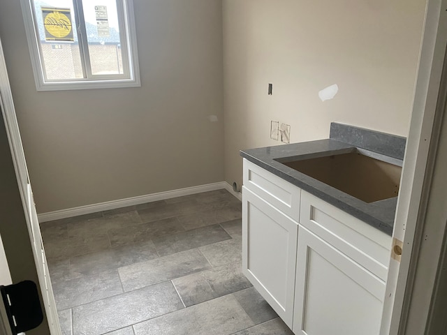 interior space with stone finish floor, baseboards, and a sink