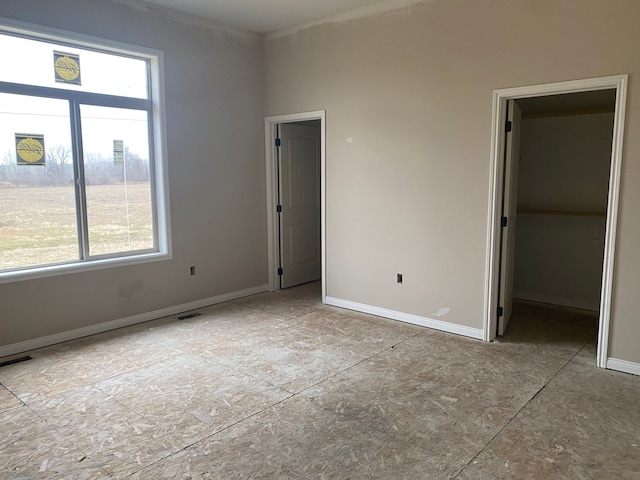 unfurnished bedroom featuring visible vents, baseboards, and a walk in closet