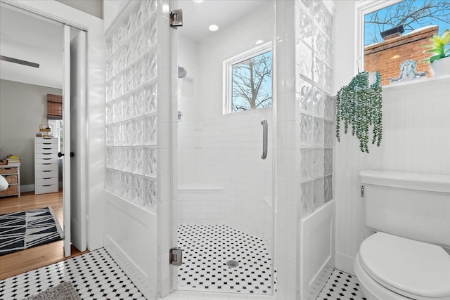 bathroom with a shower with door and toilet