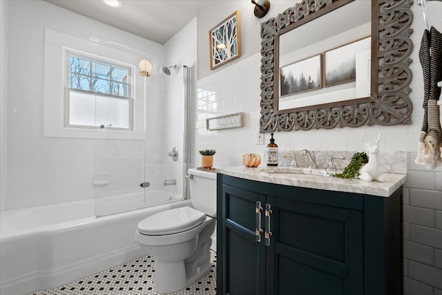 full bathroom featuring tile walls, vanity, tiled shower / bath, and toilet