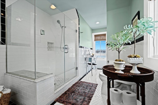 bathroom with tile walls, a shower with door, toilet, and tile patterned floors