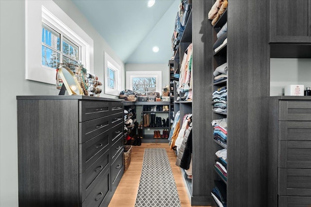 spacious closet with light hardwood / wood-style flooring and lofted ceiling