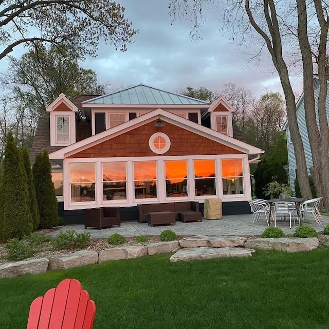 rear view of property with an outdoor living space, a patio area, and a lawn