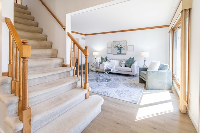 staircase featuring ornamental molding and wood finished floors