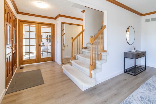 foyer entrance with wood finished floors, visible vents, french doors, and ornamental molding